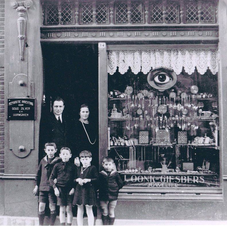 Historische zwart-witfoto van de winkelpui van Oonk met familie voor de etalage